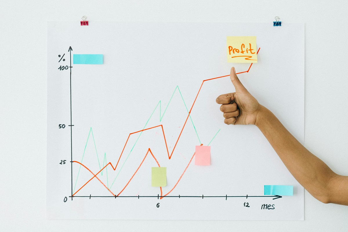 line graph showing an upward trend, alongside a sticky note labeled 'profit' and a person giving a thumbs up
