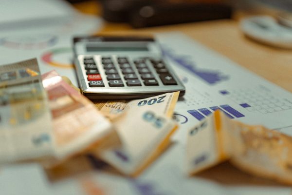 calculator, graphs, and bank notes on a desk