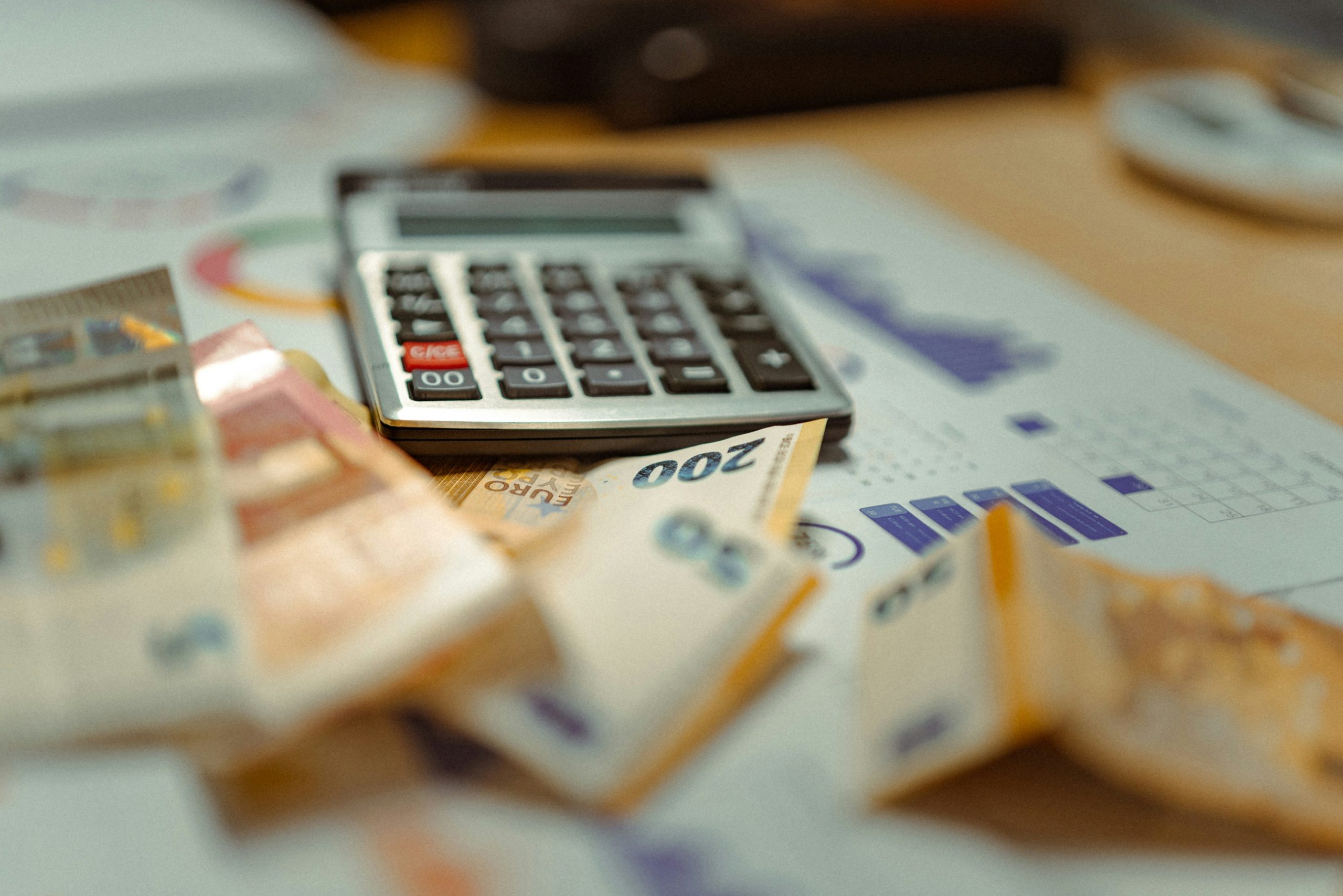 calculator, graphs, and bank notes on a desk